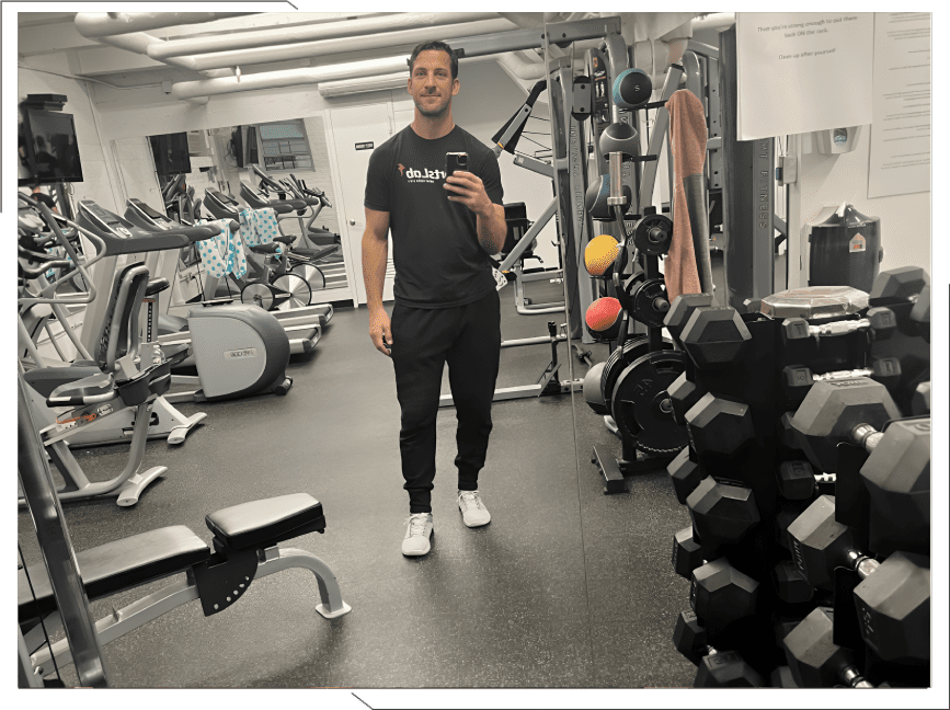 Man taking selfie in gym with equipment.