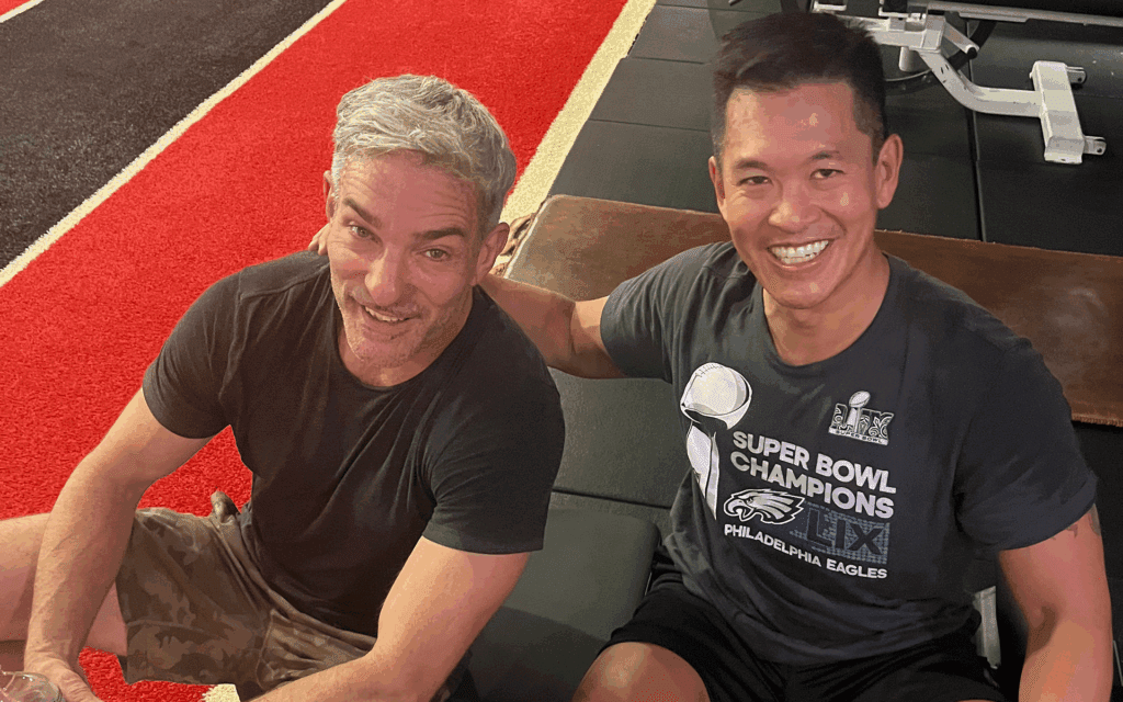 Two men smiling at the gym floor.