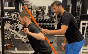 Trainer assisting man with exercise form.