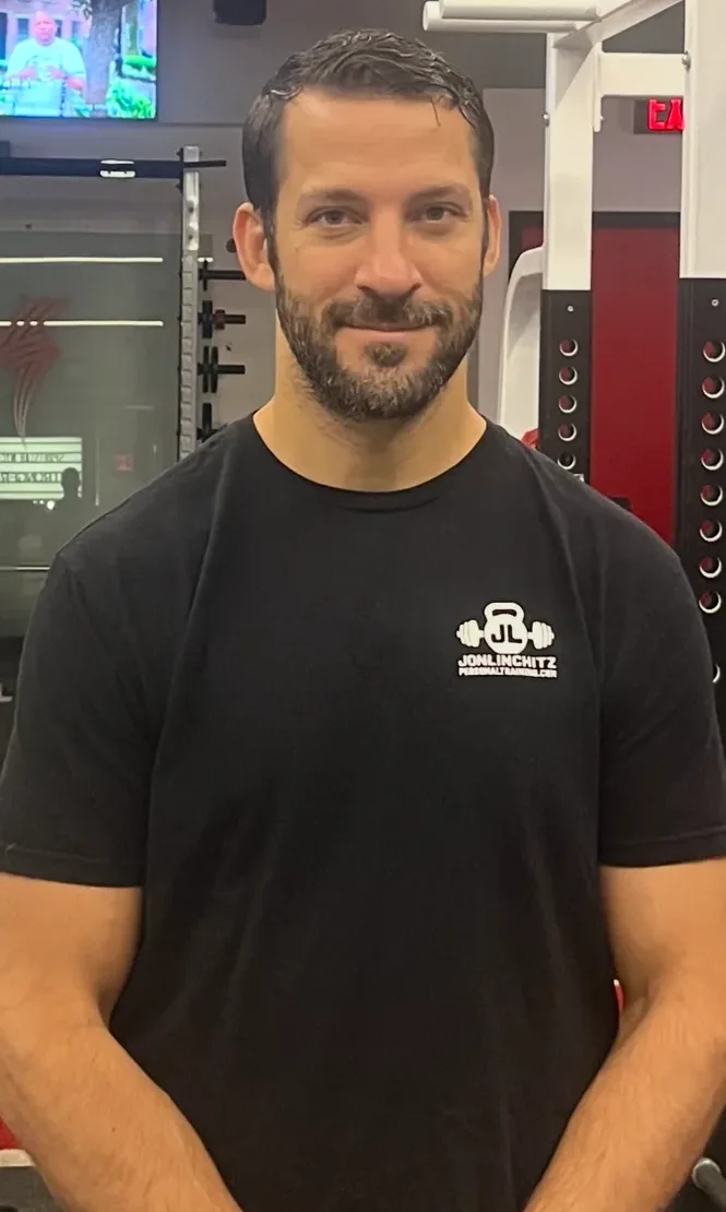 Man in a black t-shirt smiling indoors.